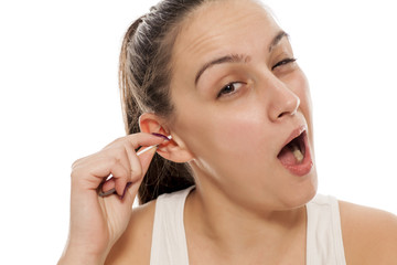 a young woman cleans her ears with a cotton swab