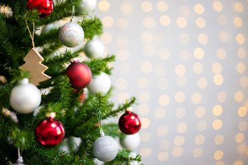 christmas and new year background - decorated christmas tree over white wall with lights