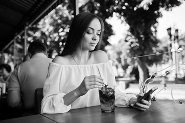 Portrait of an attractive young businesswoman with a mojito cocktail texting a message on her smatphone. Black and white photo.