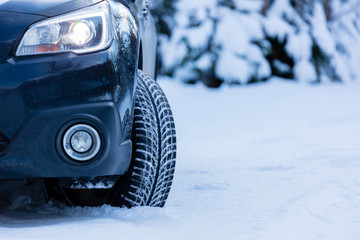 Winter tire. Front view of SUV car with headlights on.