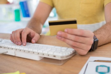 Male executive doing online shopping on computer at desk