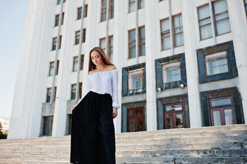 Portrait of a fabulous young successful woman in white blouse and broad black pants posing on the...
