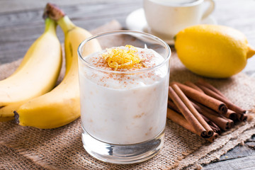Banana yogurt and fresh bananas on a wooden background