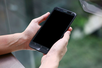 Black screen smarphone carry on hand with blur background.