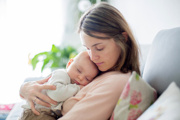 Obraz na płótnie Canvas Young mother, holding tenderly her newborn baby boy