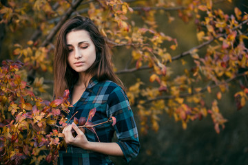 Outdoor atmospheric lifestyle photo of young beautiful lady in autumn park. Brown hair and eyes. Warm autumn forest. Copy space