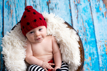 Little baby boy with knitted hat in a basket, happily smiling