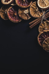 Dried oranges and lemons with cinnamon on a black background