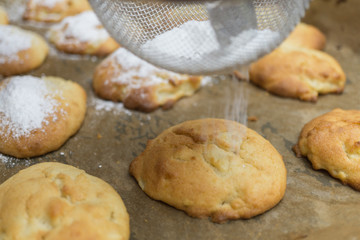 Homemade little apple cakes on baking tray, sieving icing sugar