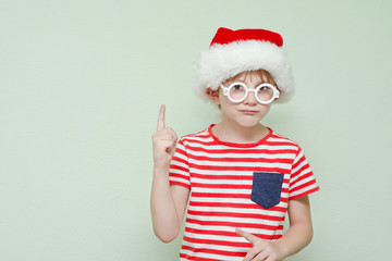 Fototapeta na wymiar Boy in Santa hat with glasses threatens finger. Portrait
