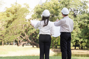 asian men and women engineers work on plans construction  in the park