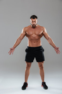 Full length portrait of a confident strong shirtless male bodybuilder