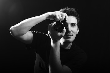 Photographer with film camera on black background.