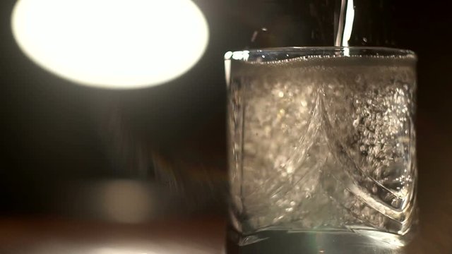 Pour soda water into a glass on a dark background focus   