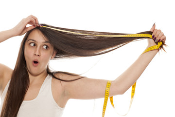 a young lady shows her long hair with a measuring tape