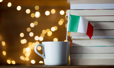 White cup with italy flag near books