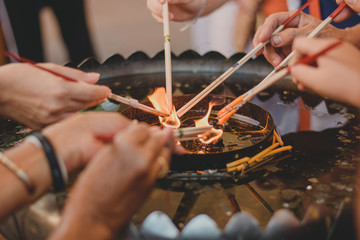 Close-up of hands with candle and incense sticks