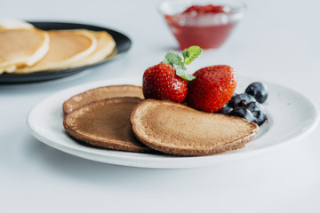 plate with delicious pancakes and berries on white table