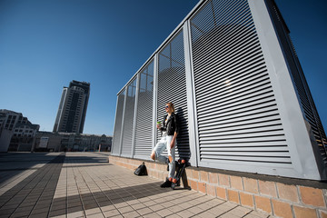 Girl with a skateboard and a cup of coffee in the cityscape