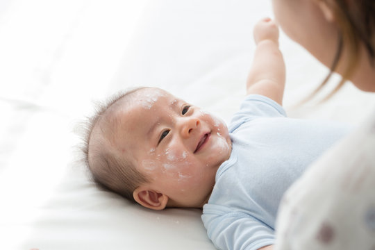Mother applying baby powder on the face newborn