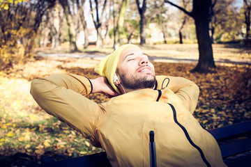 Young man in nature listening music . Autumn season.