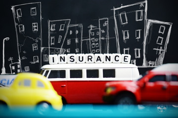 Car insurance concept with miniature toy cars and urban silhouette on dark background