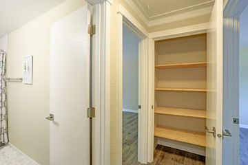 White door opens to a kitchen pantry filled with wooden shelves