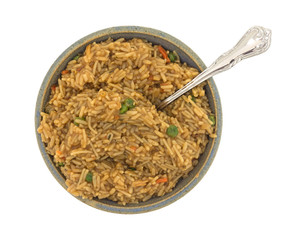 Top view of a stoneware bowl filled with cooked beef flavored rice plus a fork in the food isolated on a white background.