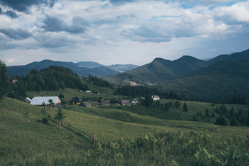 Fototapeta premium Carpathian mountains summer landscape with cloudy sky and village, natural summer travel background