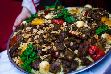 Traditional oriental pilaf on a round platter in the hands of the waiter