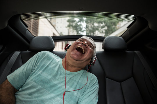 Happy senior man listening music in the car