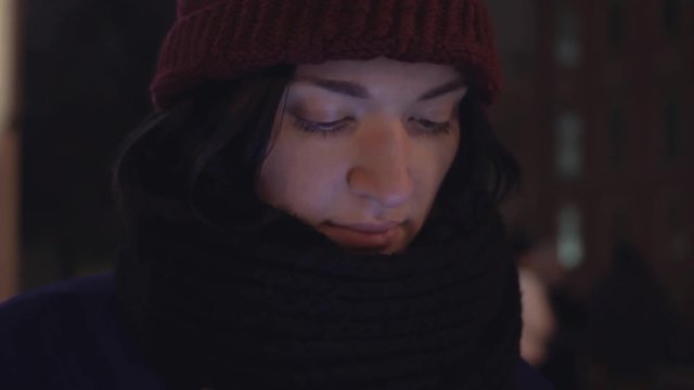 Close up of young woman dressed in jacket and knitted scarf using smartphone