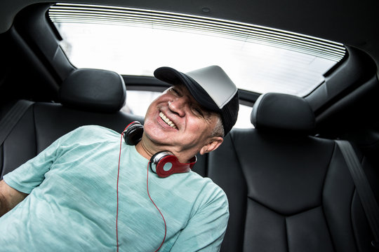 Happy senior man listening music in the car