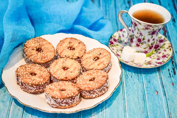 a plate with a shortbread cookie and a cup of black tea with pieces of sugar on a blue wooden background. Vegetarian breakfast