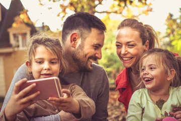Fototapeta premium Little girl want to take a selfie with sister and parents.