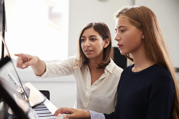 Female Pupil With Teacher Playing Piano In Music Lesson © Monkey Business
