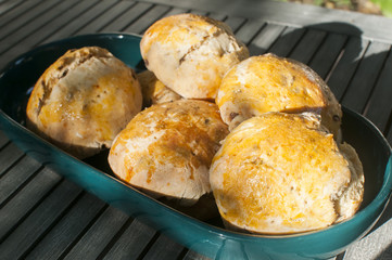 Freshly baked home-made bread rolls in porcelain dish closeup on rustic wooden table