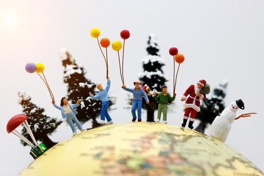 Miniature people: Santa Claus, chlidren and snowman  with Christmas tree on globe.