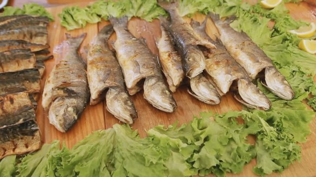 Cooked fish with salad on the table at the street food festival.