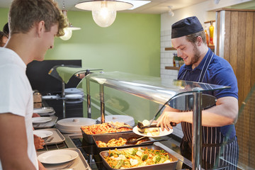 Teenage Students Being Served Meal In School Canteen