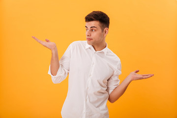 Confused man in white shirt shrugs his shoulder