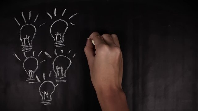 Timelapse footage of woman hand drawing light bulb on the blackboard with a chalk