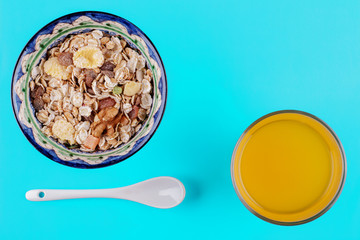 Healthy breakfast. Ceramic bowl with oat flakes, dried fruits, nuts on blue background