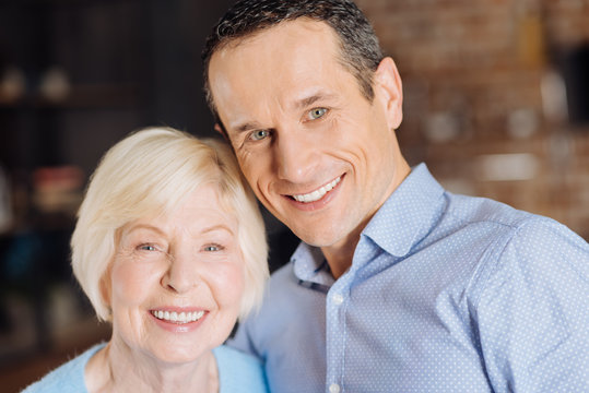 Family Portrait. The Portrait Of A Cheerful Elderly Woman And Her Charming Young Son Smiling Brightly At The Camera