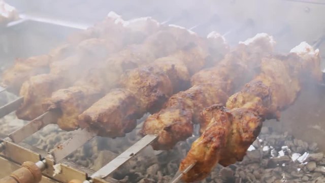Fresh meat barbecue on skewers close up. Grilled meat cooking at the bbq street food festival. Slow motion.