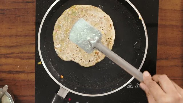 Preparing stuffed paratha on a pan with oil -Top angle