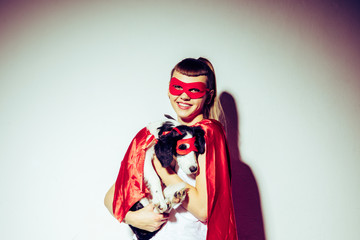 portrait of smiling woman holding puppy in superhero costume