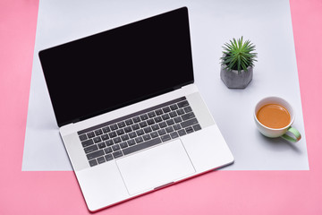 Laptop and coffee cup on color background. View from above