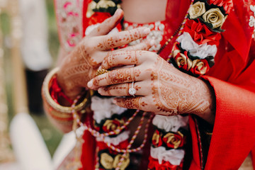 Tender hands of an Indian bride covered with henna tattoo and wedding ring on her finger