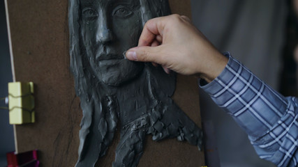 Close-up of Sculptor creating sculpture of woman's face on canvas in art studio